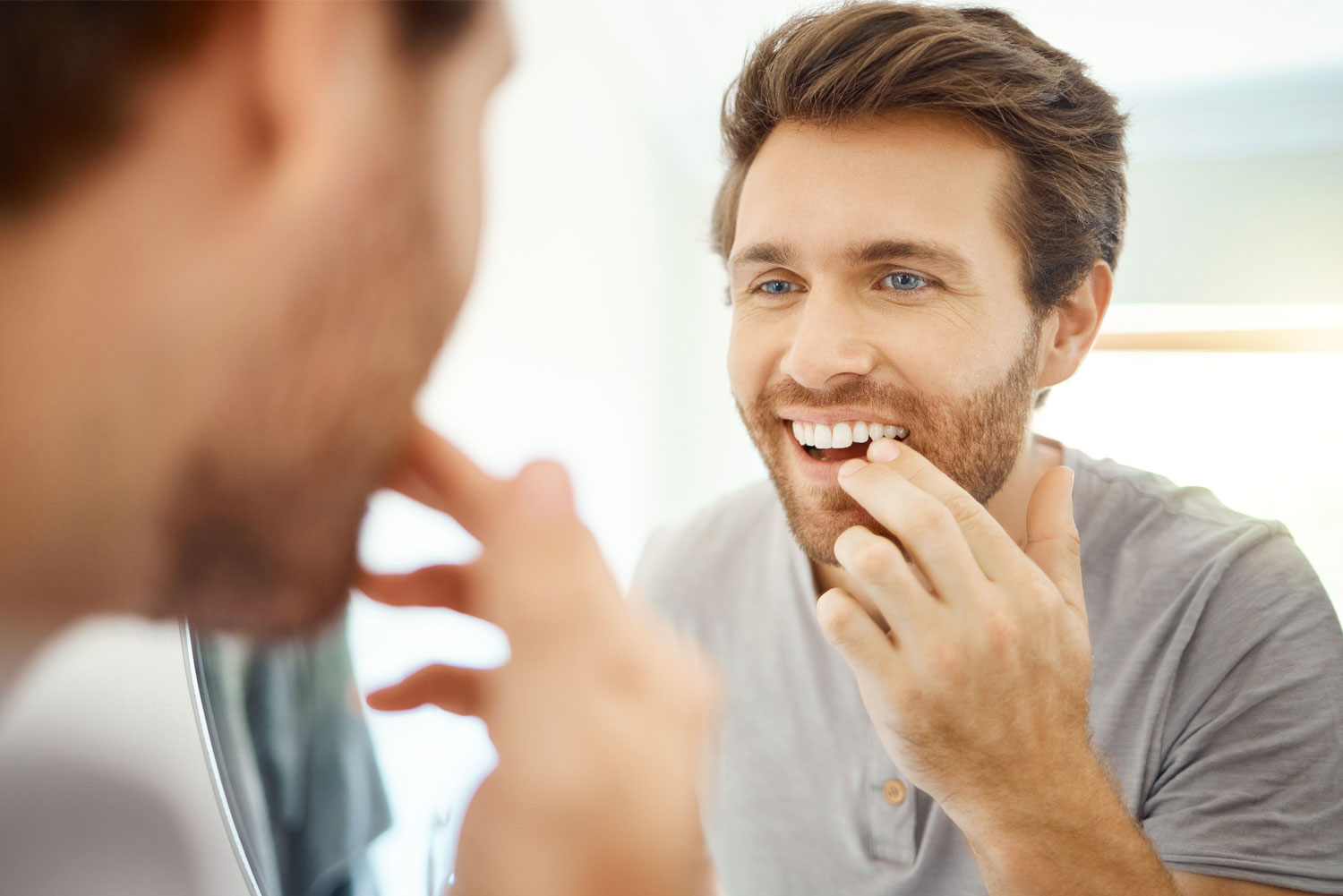 Man Checking his teeth in the mirror in his morning routine
